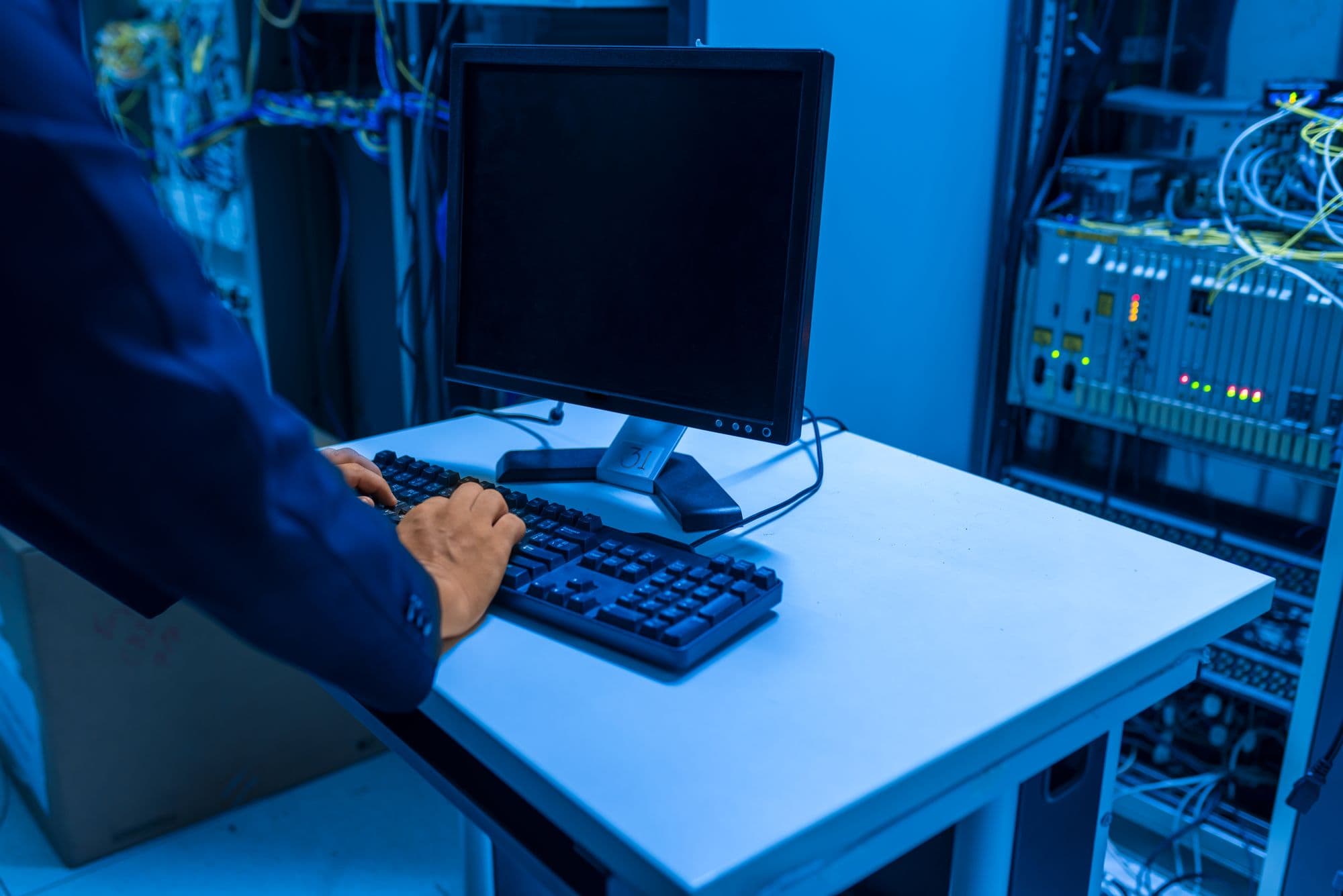 IT engineer typing at a console in a server room